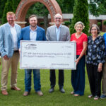 Pictured with campus background holding a ceremonial check at the Chuck Wisdom Jr. Agricultural Heritage Scholarship Endowment presentation are (from left) Gus Wisdom, Callie Creed, Garland Rice, Colt Rice, Butch Rice, Karen Wisdom, Gerre Wisdom, Chuck Wisdom Sr. and Christi DeLine.