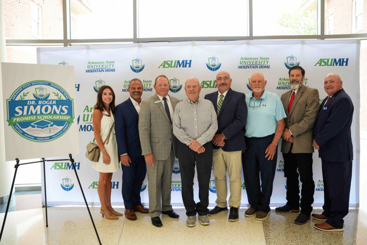Pictured standing in front on ASU-Mountain Home backdrop are (from left) Heather Maxey, ASU System Board of Trustees; Dr. Todd Shields, ASU System President; Dr. Bentely Wallace, ASUMH Chancellor; Dr. Roger Simons, donor; Wes Henderson, Yellville-Summit School District Superintendent; Richard Blevins, Norfork School District Superintendent; Kelvin Hudson, Flippin School District Superintendent; Jayme Jones, Cotter Public School District Superintendent